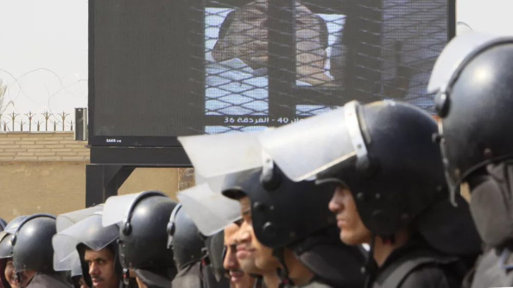 Egyptian anti-riot soldiers line up under a giant screen showing former President Hosni Mubarak outside the police academy court in Cairo, Egypt, Monday, Aug. 15, 2011. Former President Hosni Mubarak returned to court Monday for the second session of his trial on charges of corruption and complicity in killing protesters during the mass uprising that ousted him from power. (AP Photo/Amr Nabil)