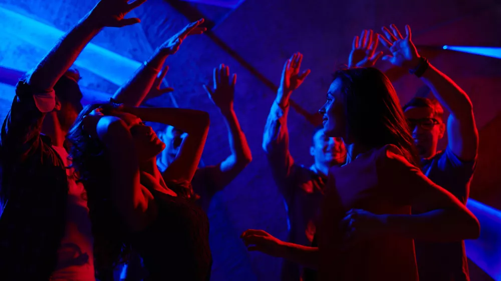 Joyful dancers with raised hands enjoying prom