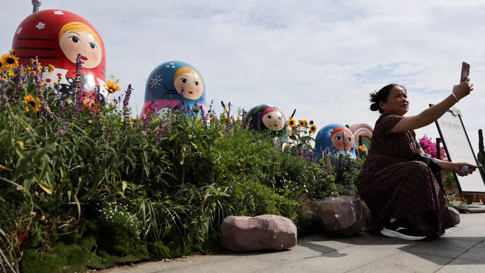 A person takes a selfie in front of Russian nesting dolls at the North Bund, ahead of Russian President Vladimir Putin's visit to China, in Shanghai, China, May 19, 2026. REUTERS/Go Nakamura