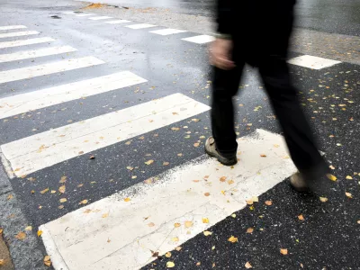 Man in black crossing street on wet autumn day