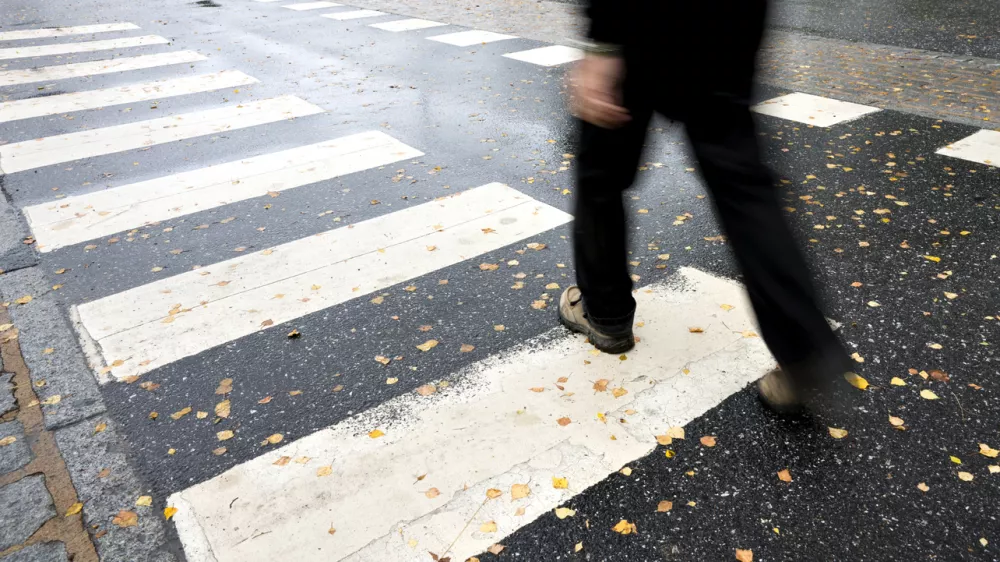 Man in black crossing street on wet autumn day