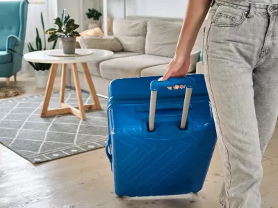 Unrecognizable woman leaving home with a suitcase going on a trip or vacation.