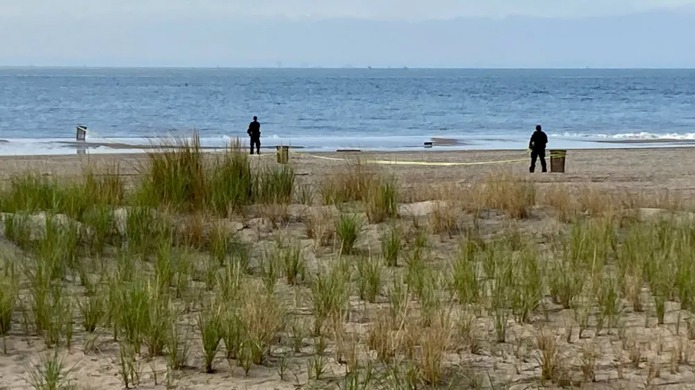 FILE - New York Police investigators examine a stretch of beach at Coney Island where three children were found dead in the surf, Sept. 12, 2022, in New York. (AP Photo/Joseph Frederick, File)