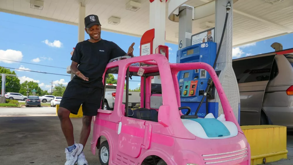Mali Hightower, 29, poses with what he describes as a self-created gas saver, a pink Power Wheels Barbie Dream Camper, at a gas station in Ellenwood, Georgia, U.S., May 18, 2026. REUTERS/Jayla Whitfield-Anderson