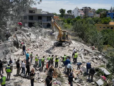 Rescue workers search for victims in the rubble of a destroyed house that was hit on Tuesday by an Israeli airstrike, in the village of Deir Qanoun al Nahr, south Lebanon, Wednesday, May 20, 2026. (AP Photo/Mohammed Zaatari)