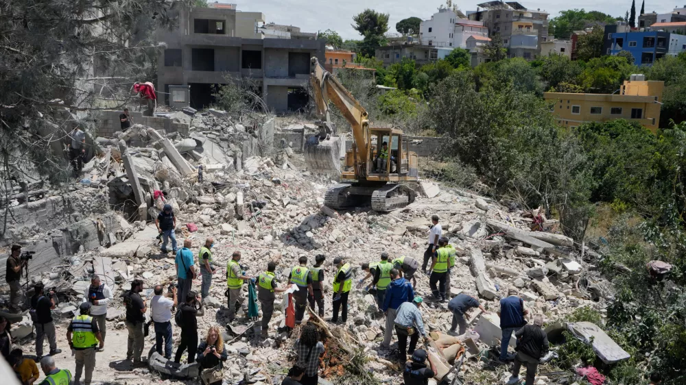 Rescue workers search for victims in the rubble of a destroyed house that was hit on Tuesday by an Israeli airstrike, in the village of Deir Qanoun al Nahr, south Lebanon, Wednesday, May 20, 2026. (AP Photo/Mohammed Zaatari)