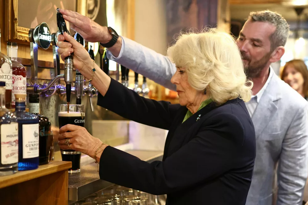 Britain's Queen Camilla pours a pint of Guinness in The Parson's Nose pub, in the village of Hillsborough, on day two of the royal visit to Northern Ireland, Wednesday May 20, 2026. (Henry Nicholls/PA via AP)