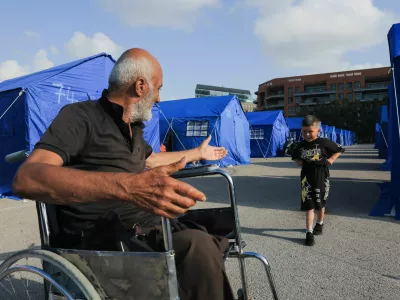 Mohamad Saaydoun, 69, displaced from Beirut's southern suburbs, suffering from injuries after he survived an Israeli strike when he was fleeing home, who had previously lost part of his leg due to diabetes and a medical condition and later lost the rest of his leg in the strike, plays with his grandchild outside his tent at the Beirut waterfront, in Beirut, Lebanon, May 21, 2026. REUTERS/Raghed Waked