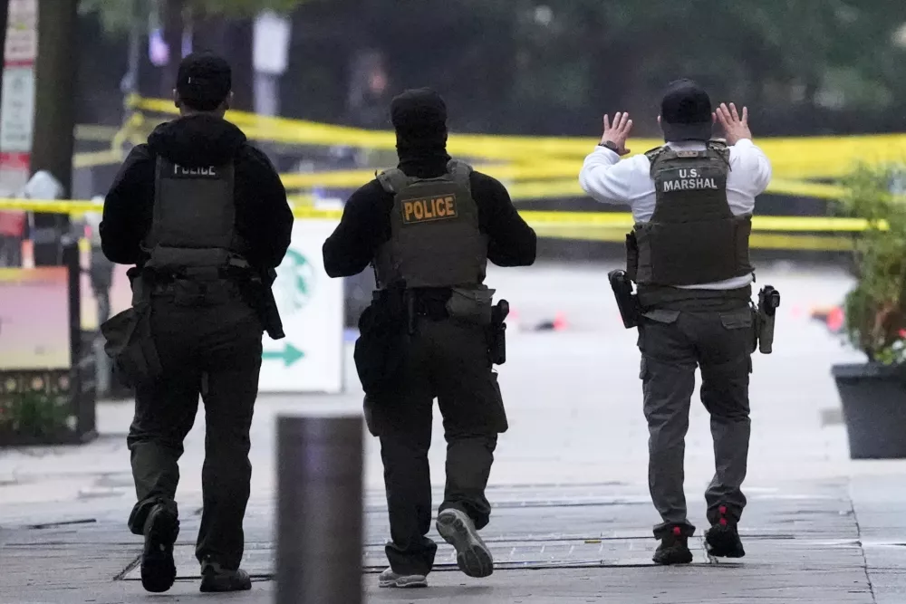 U.S. Marshals and other police walk toward a crime scene after responding to reports of shots fired near the White House, Saturday, May 23, 2026, in Washington. (AP Photo/Alex Brandon)