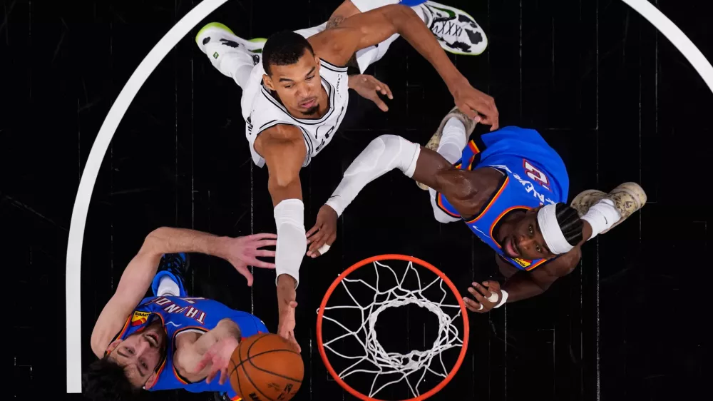San Antonio Spurs forward Victor Wembanyama (1) drives to the basket against Oklahoma City Thunder center Chet Holmgren (7) and guard Shai Gilgeous-Alexander (2) during the first half in Game 4 in the Western Conference finals NBA basketball playoffs series in San Antonio, Sunday, May 24, 2026. (AP Photo/Eric Gay)