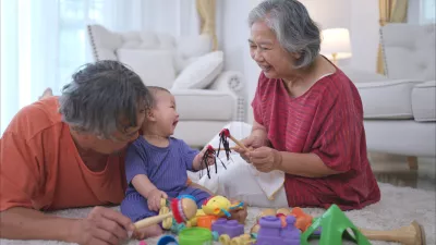 Grandparents and their little grandchild play happily in the living room of the house