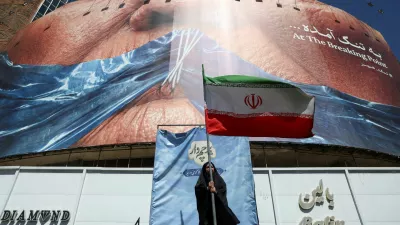 A woman holds an Iranian flag near an anti-U.S. billboard depicting U.S. President Donald Trump and the Strait of Hormuz, in Tehran, Iran, May 25, 2026. Majid Asgaripour/WANA (West Asia News Agency) via REUTERS ATTENTION EDITORS - THIS PICTURE WAS PROVIDED BY A THIRD PARTY