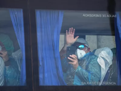A passenger waves inside a bus after being disembarked from the hantavirus-stricken cruise ship MV Hondius at the port of Granadilla in Tenerife, Canary Islands, Spain, Sunday, May 10, 2026. (AP Photo/Manu Fernandez)