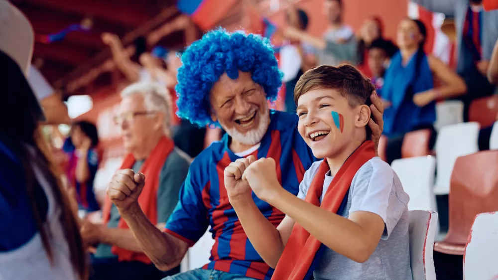 Happy boy and his grandfather cheering during sports game at the stadium. / Foto: Drazen Zigic