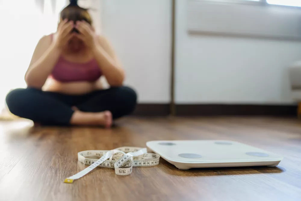 Obese Woman with fat upset bored of dieting Weight loss fail&Acirc;&nbsp; Fat diet and scale sad asian woman on weight scale at home weight control. / Foto: Dacharlie Getty Images