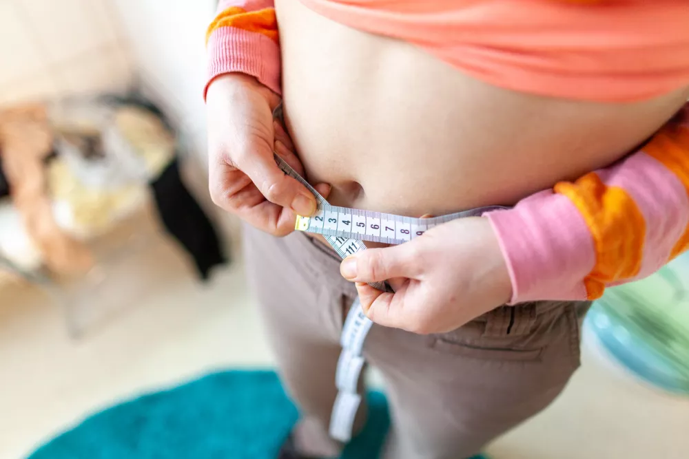 woman measures her abdomen with a measuring tape / Foto: Huettenhoelscher,getty Images