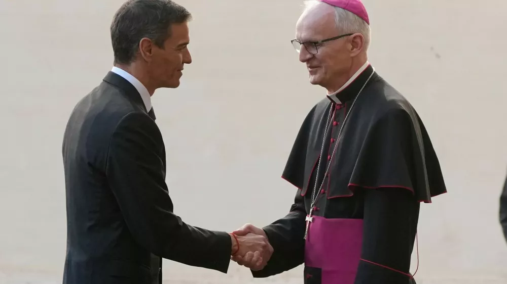 Spain's Premier Pedro Sanchez is welcomed by Archbishop Petar Rajic, Prefect of the Prefecture of the Papal Household as he arrives at the St. Damasus courtyard ahead of their private audience with Pope Leo XIV at the Vatican, Wednesday, May 27, 2026. (AP Photo/Alessandra Tarantino)