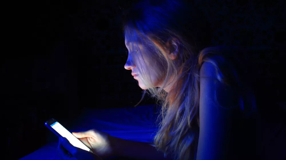 young woman using the smart phone on bed before sleep