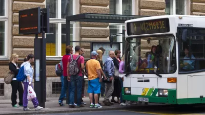 Ljubljana, Slovenia - july 26, 2011: A view of the people in line and slowly going on the bus at bus station in front of main Post office in center of Ljubljana. On left side is panelwith bus line nimber and time when it will leave.