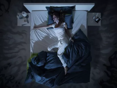 Nervous woman suffering from insomnia and lying in bed late at night, she is awake and restless, top view