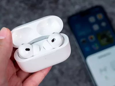 Jurmala, Latvia - 21 09 2023: In woman hand there is open case with headphones - AirPods Pro 2 generation. On background out of focus smartphone witch are connected to Air Pods.