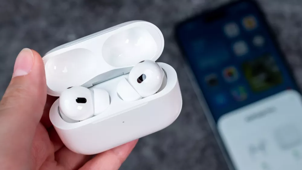 Jurmala, Latvia - 21 09 2023: In woman hand there is open case with headphones - AirPods Pro 2 generation. On background out of focus smartphone witch are connected to Air Pods.