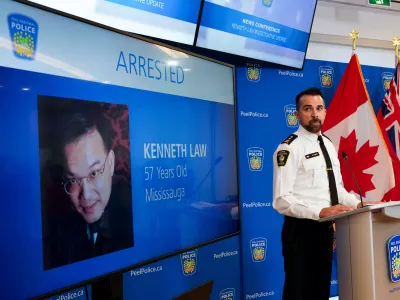 FILE - York Regional Police Inspector Simon James speaks during a news conference in Mississauga, Ont., Aug. 29, 2023, with the image of Kenneth Law, a Canadian man accused of selling lethal substances on the internet to people at risk of self harm, displayed on screen. (Arlyn McAdorey/The Canadian Press via AP, File)