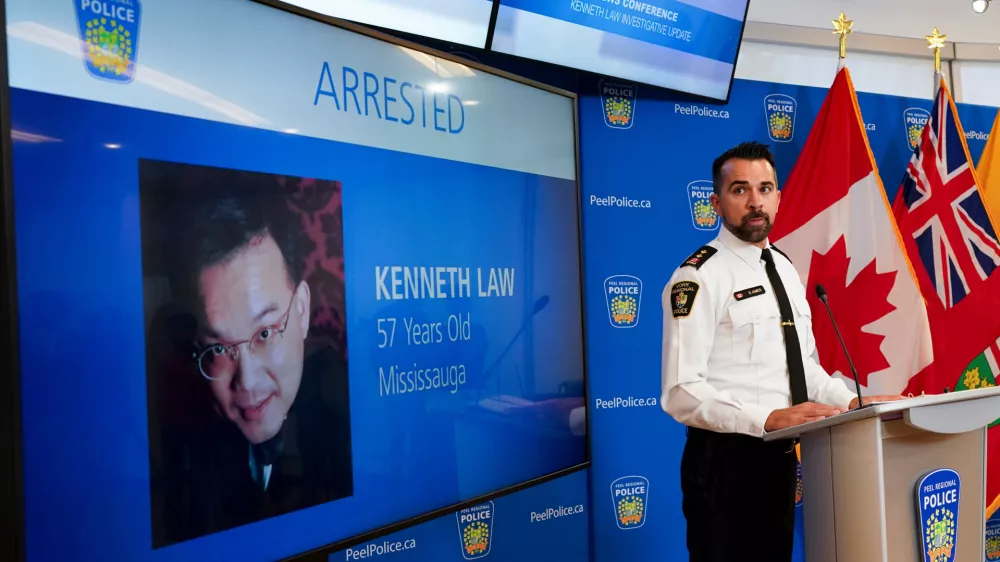 FILE - York Regional Police Inspector Simon James speaks during a news conference in Mississauga, Ont., Aug. 29, 2023, with the image of Kenneth Law, a Canadian man accused of selling lethal substances on the internet to people at risk of self harm, displayed on screen. (Arlyn McAdorey/The Canadian Press via AP, File)