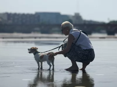 A woman tries to cool off her dog on the shallow water of the Miroir d'Eau (Mirror of Water) amid a heatwave in Bordeaux, France, May 28, 2026. REUTERS/Alice Sacco