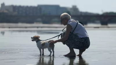 A woman tries to cool off her dog on the shallow water of the Miroir d'Eau (Mirror of Water) amid a heatwave in Bordeaux, France, May 28, 2026. REUTERS/Alice Sacco
