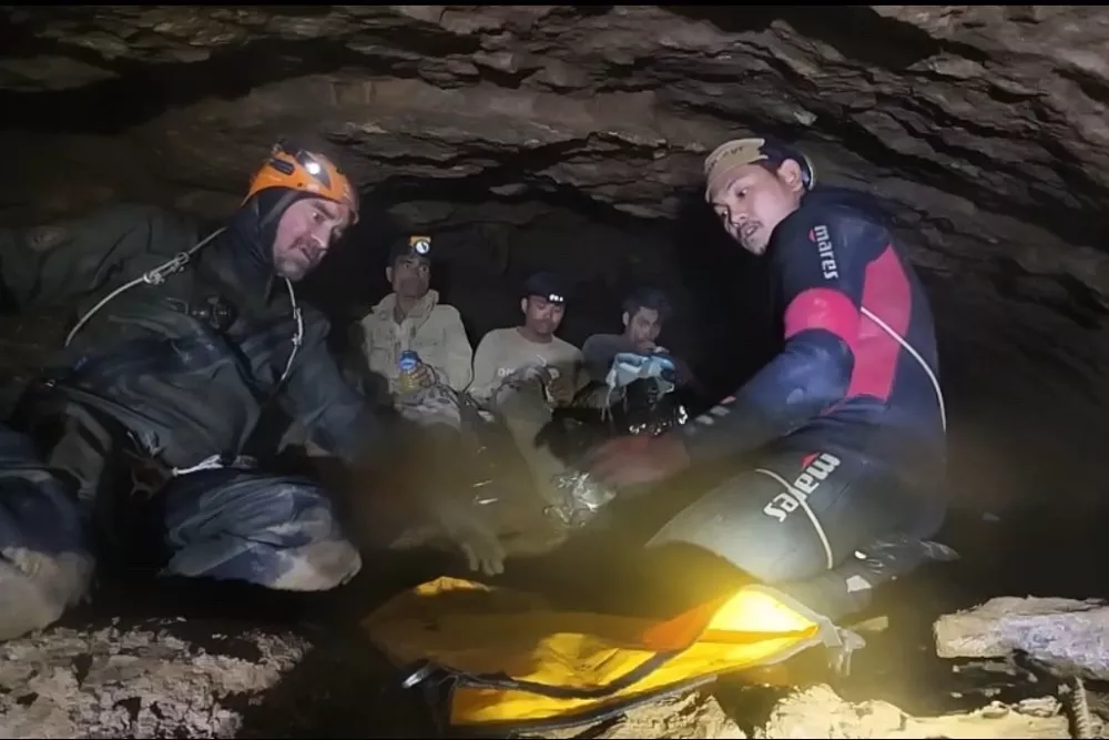 This image released by Benz Norrased Palasing Seascout Diving, two rescuers work before evacuating the first of five villagers who had been trapped in a cave, seen in the back, in Xaisomboun province, Laos, Friday, May 29, 2026. (Benz Norrased Palasing Seascout Diving via AP)