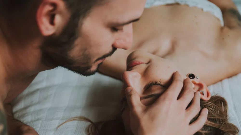 Close-Up Of Couple Embracing While Lying On Bed At Home
