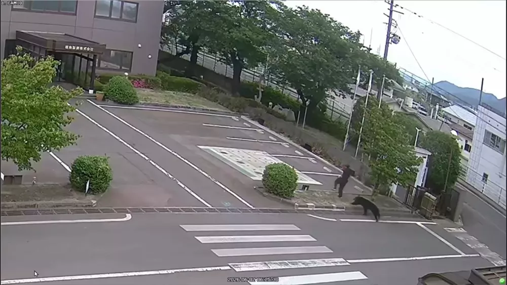 This image made from the security camera footage provided by the Fukushima Steel Works, shows a bear, right, chasing a person, second right, on its premises in Fukushima, Japan, Tuesday, June 2, 2026. (FUKUSHIMA STEEL WORKS via AP)
