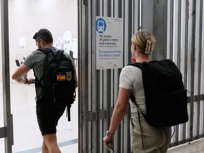 People entering the airport subway station walk past a sign announcing that due to a strike the subway will be closed, at the start of a 24-hour general strike to protest against a new labour package announced by the centre-right government, in Lisbon, Tuesday night, June 2, 2026. (AP Photo/Armando Franca)