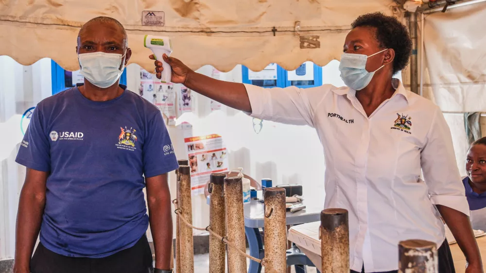 A health worker checks an individual's temperature at a temporary health clinic at the Mpondwe border crossing linking Uganda and the Democratic Republic of the Congo, Thursday, June 4, 2026. (AP Photo/Hajarah Nalwadda)