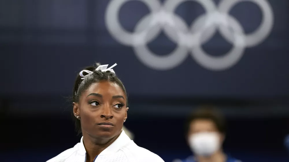 FILE - In this July 27, 2021 file photo, Simone Biles, of the United States, watches gymnasts perform after she exited the team final at the 2020 Summer Olympics, in Tokyo. Biles, who redefined excellence in gymnastics and picked up seven Olympic medals along the way, drew attention and, from some, criticism by pulling out of events in Tokyo because of a mental block that made her afraid to attempt certain dangerous moves. (AP Photo/Ashley Landis, File)