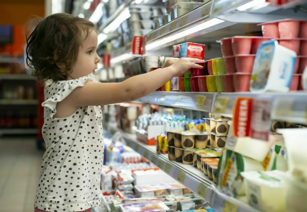 Little girl buying yogurt in supermarket. Child in supermarket select products from store showcase. Concept for children selecting milk products in shop. / Foto: Deyangeorgiev