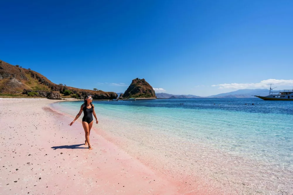 Young female tourism enjoying the tropical pink sandy beach with clear turquoise water at Komodo islands in Indonesia / Foto: Kitzcorner
