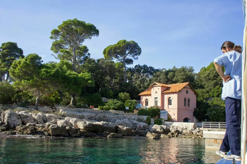 Lokrum Island, Dubrovnik, Croatia - November 10, 2015: just a 15-minute boat ride from the Old City of Dubrovnik lies the island of Lokrum, a nature reserve and Special Forest Vegetation Reserve, open to the public from April to November during the day (nobody is allowed to remain on the island at night). The shot shows one of the water taxi crew standing on the port side of the boat as we arrive at Portoc. The pink house is the fire warden's office. / Foto: Coastalrunner
