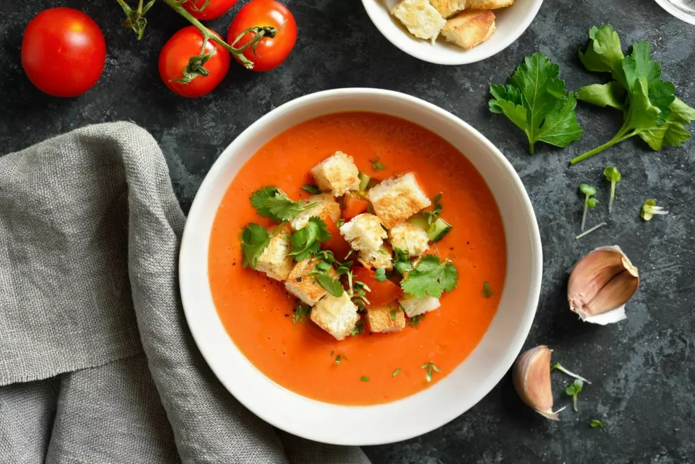 Tomato gazpacho soup in bowl over dark stone background. Healthy food concept. Top view, flat lay / Foto: Tatiana Volgutova