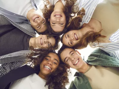 Group of diverse teenage students forms a circle, radiating togetherness and unity. They stand together, smiling at the camera, capturing harmonious school community and the spirit of teamwork. / Foto: Lacheev