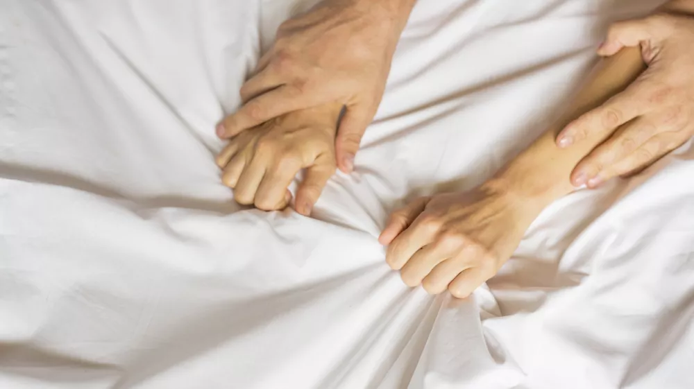 couple hands pulling white sheets in ecstasy, orgasm. Concept of passion. Orgasm. Erotic moments. Intimate concept. Sex couple. Bedroom. Hotel room. Spa / Foto: Dmitry Belyaev Getty Images/istockphoto