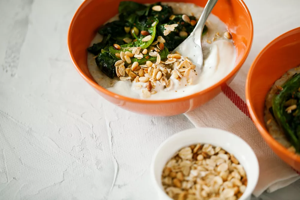 Healthy savory oatmeal with greens and Bulgarian yogurt high in fiber and protein in bowl on gray background close-up,easy to prepare for breakfast or brunch. Healthy balanced diet concept. Copy space / Foto: Darya Arnautova