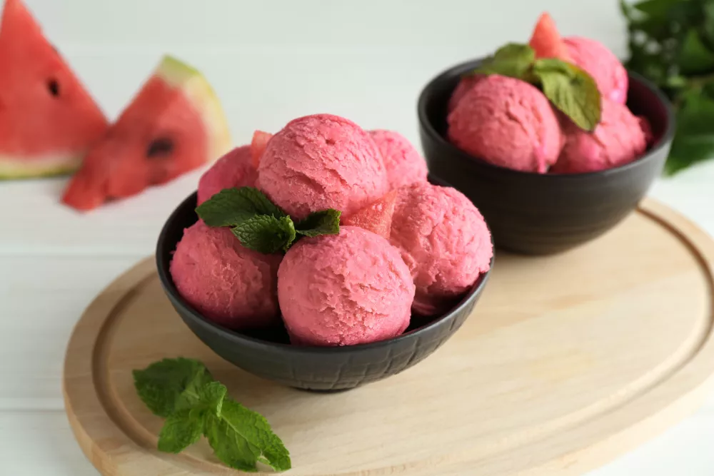 Scoops of tasty watermelon sorbet in bowls and mint on white wooden table / Foto: Liudmila Chernetska