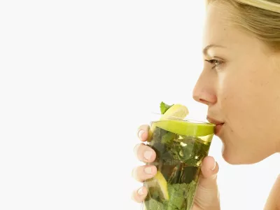 woman drinking a glass of lemon juice with mint leaves / Foto: Stockbyte