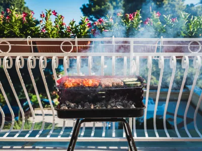 Delicious meat on barbecue grill with coal on balcony. Grilling food on a balcony or a terrace with wonderful view. Small cheap BBQ grill at home. / Foto: _jure Getty Images/istockphoto