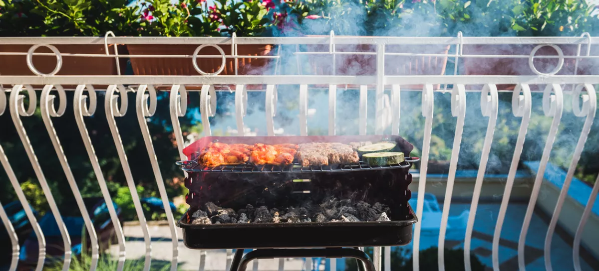 Delicious meat on barbecue grill with coal on balcony. Grilling food on a balcony or a terrace with wonderful view. Small cheap BBQ grill at home. / Foto: _jure Getty Images/istockphoto