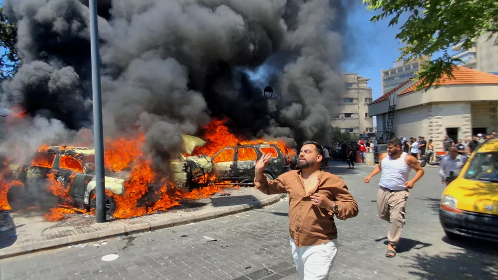 People run in front of burned cars that were attacked in an Israeli airstrike in the southern port city of Sidon, Lebanon, Wednesday, June 10, 2026. (AP Photo/Mohammed Zaatari)
