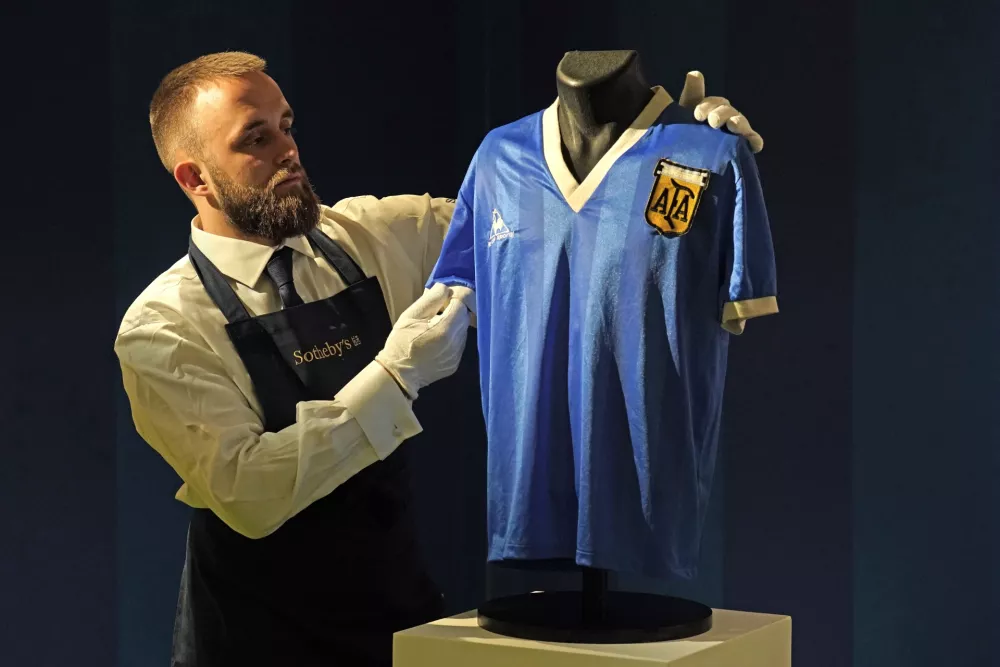 A Sotheby's gallery assistant with Diego Maradona's 1986 World Cup 'Hand of God' shirt which is on display at Sotheby's in London, before it is offered at auction. Picture date: Wednesday April 20, 2022. (Photo by Jonathan Brady/PA Images via Getty Images) / Foto: Jonathan Brady - Pa Images