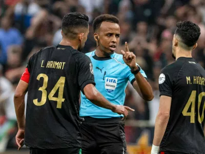 Referee Omar Artan, center, of Somalia, is confronted by players after calling a penalty kick during the CAF Champions League final soccer match between AS FAR Rabat and Mamelodi Sundowns, in Rabat, Morocco, Sunday, May 24, 2026. (AP Photo/Mosa'ab Elshamy)
